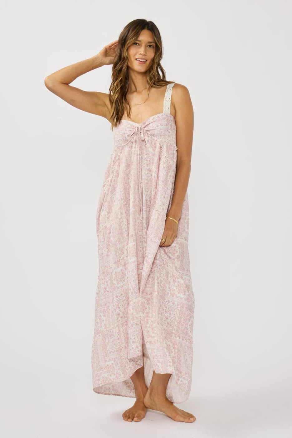 Woman wearing a long, light pink dress with a subtle pattern on a white background