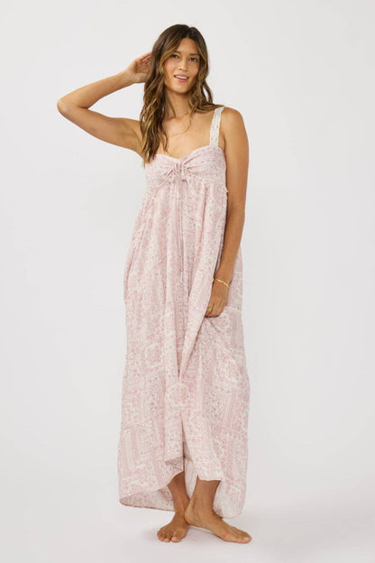 Woman wearing a long, light pink dress with a subtle pattern on a white background