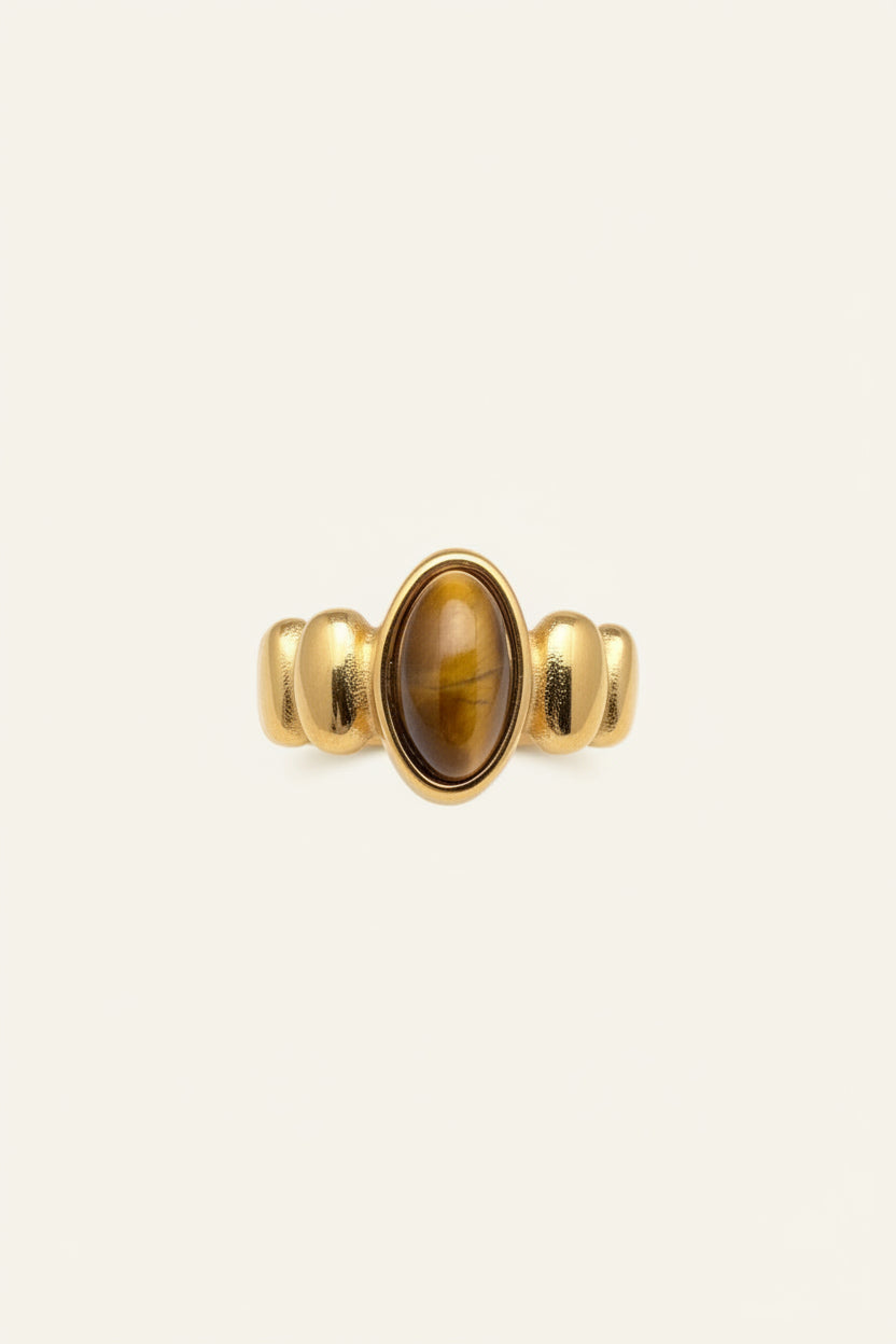 Gold ring with a yellow gemstone on a hand against a dark background