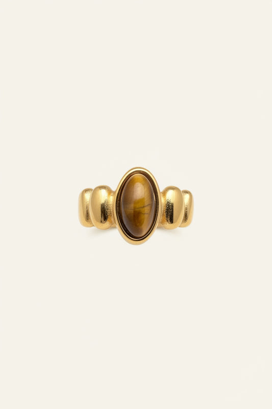 Gold ring with a yellow gemstone on a hand against a dark background
