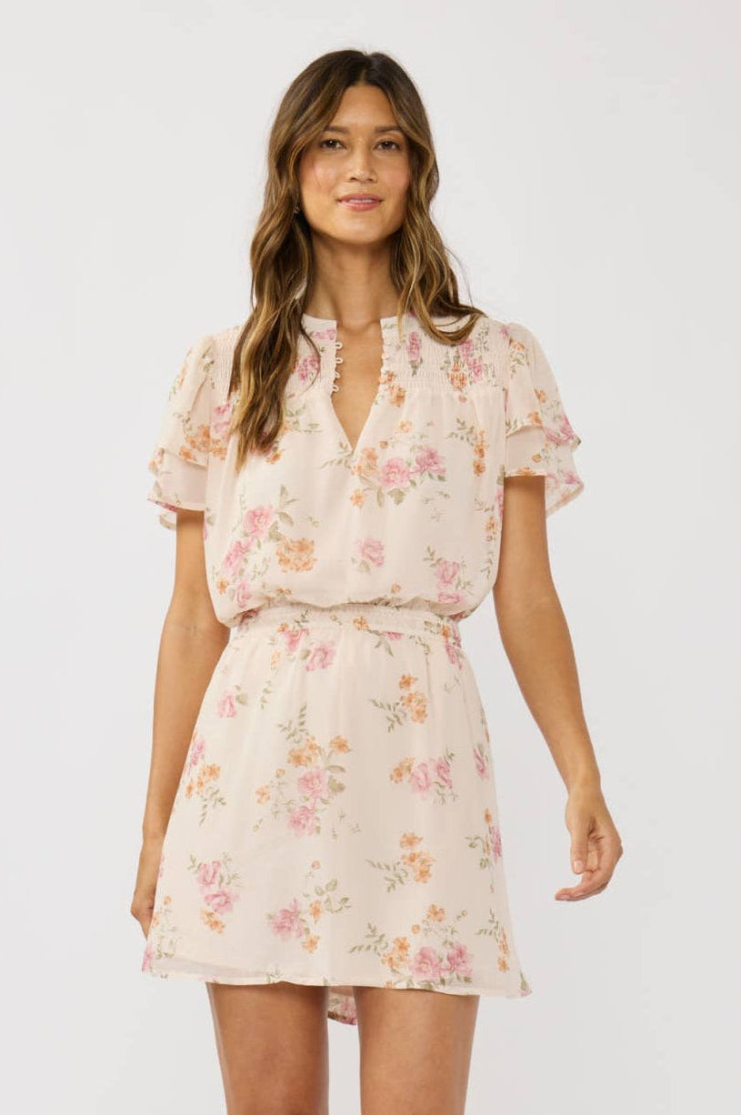 Woman wearing a cream floral dress on a white background