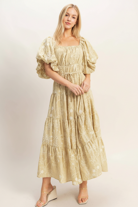 Woman wearing a yellow dress with puff sleeves against a plain background